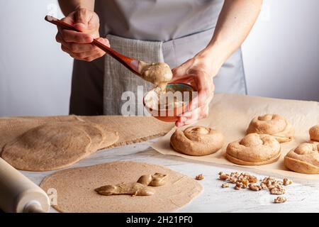 gros plan image isolée d'une femme caucasienne préparant des rouleaux de pâtisserie turque douce avec tahini et pétimezi (tahin pekmez) elle mélange les ingrédients et Banque D'Images