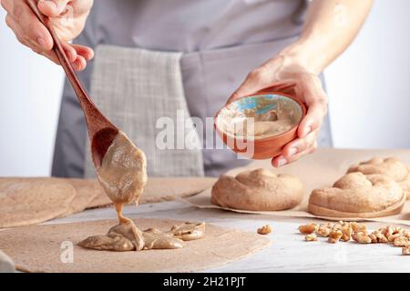 gros plan image isolée d'une femme caucasienne préparant des rouleaux de pâtisserie turque douce avec tahini et pétimezi (tahin pekmez) elle mélange les ingrédients et Banque D'Images