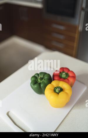 Gros plan à grand angle de trois poivrons sur une planche dans la cuisine Banque D'Images