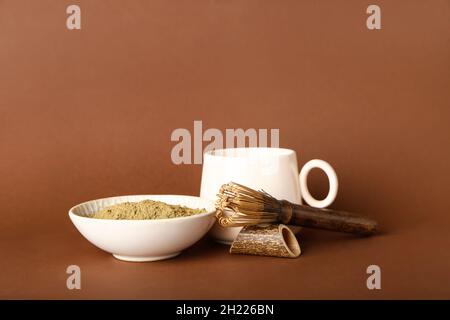 Bol avec poudre de hojicha, tasse de thé et chasen sur fond marron Banque D'Images