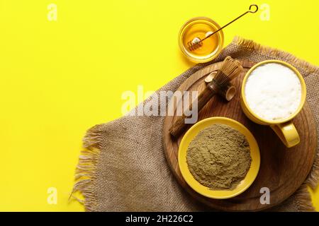Bol avec poudre de hojicha, miel, tasse de thé et chasen sur fond jaune Banque D'Images