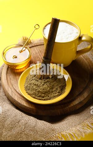 Bol avec poudre de hojicha, miel, tasse de thé et chasen sur fond jaune Banque D'Images