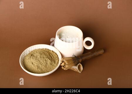 Bol avec poudre de hojicha, tasse de thé et chasen sur fond marron Banque D'Images