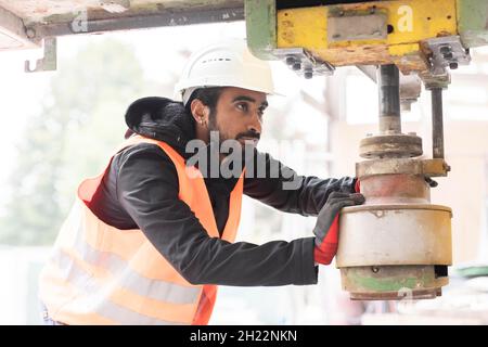 Un technicien de barbe et de casque travaille dans un atelier, Fribourg, Bade-Wurtemberg, Allemagne Banque D'Images