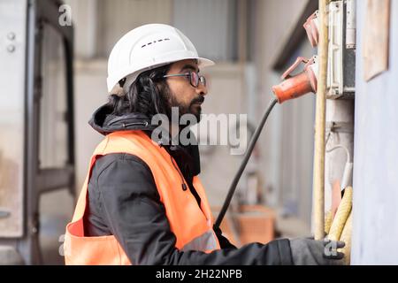 Un technicien de barbe et de casque travaille dans un atelier, Fribourg, Bade-Wurtemberg, Allemagne Banque D'Images