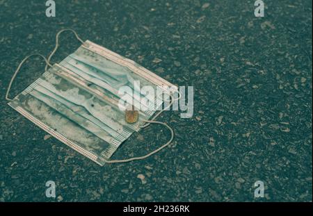 Le masque médical utilisé doit être mis au rebut sur le sol.Élimination des déchets médicaux sans hygiène.Masque facial poubelle sur le sol.Masque chirurgical bleu sale Banque D'Images