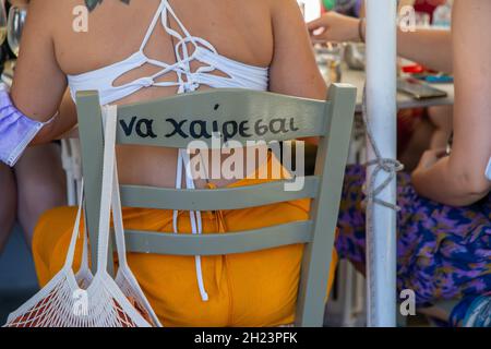 Panneau à l'arrière d'une chaise sur l'île de Tinos, Grèce disant "soyez heureux" Banque D'Images