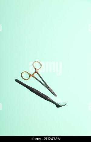 Outils en métal pour dentiste avec miroir sur fond vert menthe.Minimalisme.Concept de soins dentaires. Banque D'Images
