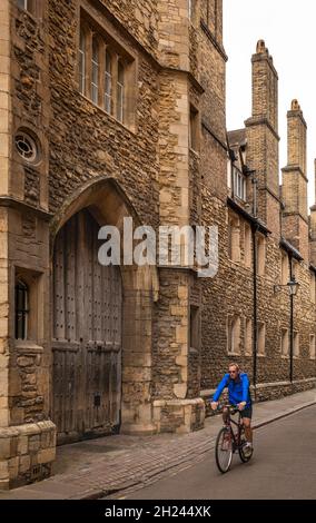 Royaume-Uni, Angleterre, Cambridgeshire, Cambridge, Trinity Lane,Cycliste passant devant la porte de la Reine dans l'ancien mur de pierre de Trinity College Banque D'Images