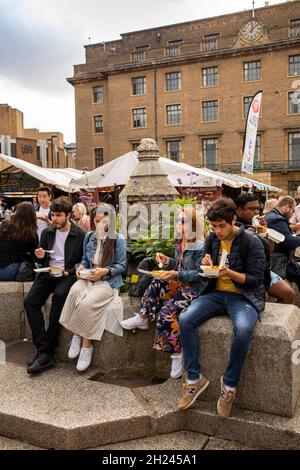 Royaume-Uni, Angleterre, Cambridgeshire, Cambridge, Market Square,les personnes qui mangent de la nourriture à emporter à la fontaine centrale Banque D'Images