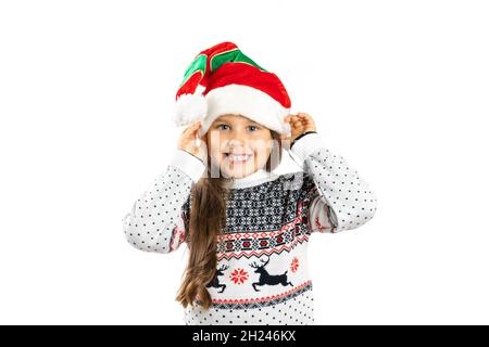 Portrait en gros plan d'une fille souriante et positive en tricot blanc chandail de Noël avec renne tenant un chapeau de gnome avec les mains, isolé sur blanc Banque D'Images