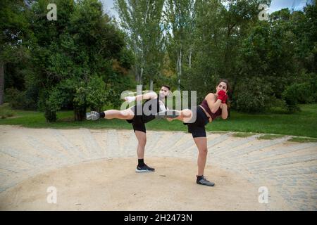 un jeune caleçon de boxe caucasien, homme et femme, s'entraîne en kick dans un parc Banque D'Images