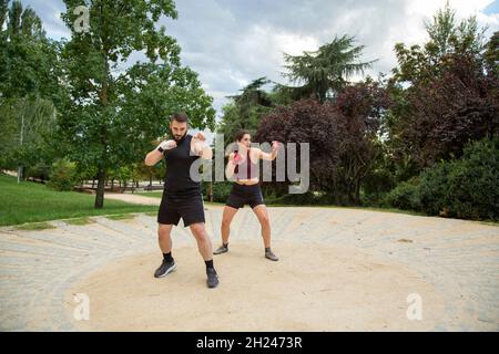 Un jeune caleçon caucasien, homme et femme, entraîne la boxe dans un parc Banque D'Images