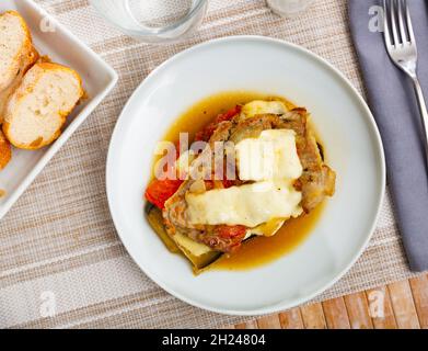 Aubergines avec viande hachée et fromage servis sur une assiette blanche avec des morceaux de service. Banque D'Images