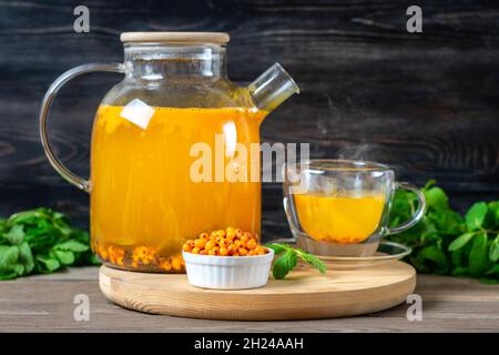Théière et tasse de délicieux et aromatique thé d'argousier avec menthe et miel sur table en bois utile a anti-inflammatoires et anti-stress effets Wi Banque D'Images