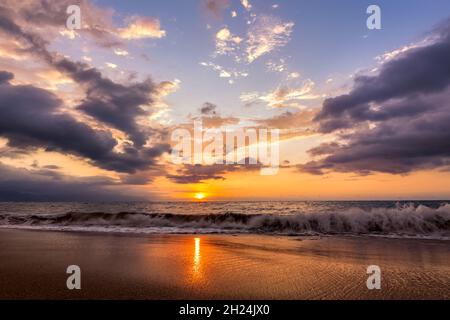 Un magnifique coucher de soleil coloré sur l'océan tandis Qu'Une vague s'écrase sur la Sandy Shore Banque D'Images