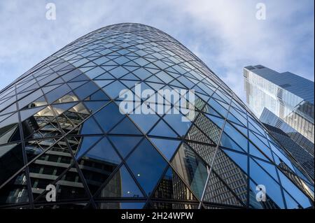 Une vue panoramique sur la façade courbée du bâtiment Gherkin avec un autre gratte-ciel en arrière-plan dans la ville de Londres, en Angleterre. Banque D'Images