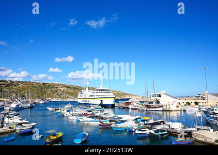 Bateau de pêche colorés amarrés dans le port avec le Gozo ferry amarré dans le port à l'arrière, Mgarr, Gozo, Malte, l'Europe. Banque D'Images