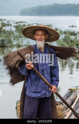 Un pêcheur cormorant au cap traditionnel sur un radeau de bambou sur la rivière Li.Xingping, Chine. Banque D'Images
