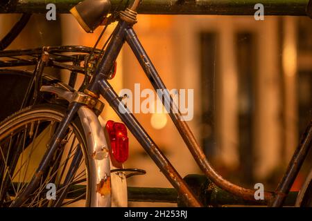 Pays-Bas.Nuit sur le front de mer d'Amsterdam.Vieux vélo rouillé près de la clôture à la lumière d'une lanterne avec une toile d'araignée et une araignée Banque D'Images