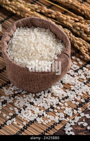 Riz comestible blanchi blanc brut poli sur fond de table en bois dans un bol, concept de conception biologique. Banque D'Images