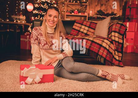 Portrait d'une femme gaie attrayante assise sur le sol reposant festal jour heure du pôle nord à la maison moderne loft à l'intérieur Banque D'Images