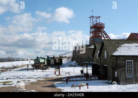 Big Pit, musée de l'exploitation minière, train à vapeur et wagons enroulement bâtiments engrenage bleu ciel bleu ciel blanc moelleux nuages hiver neige Blaenafon Wales UK Copy space Banque D'Images