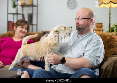 Le père s'éloigne d'un baiser du chien déchiqueuse et le reste de la famille rit. Banque D'Images