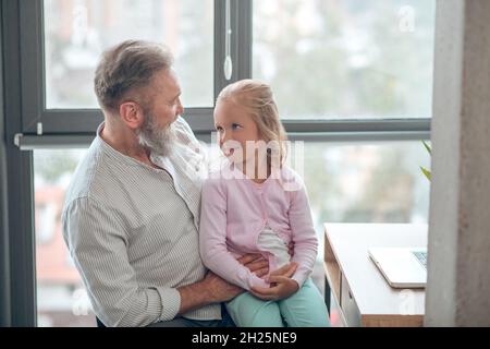 Un homme d'affaires assis à la table et tenant sa petite fille Banque D'Images
