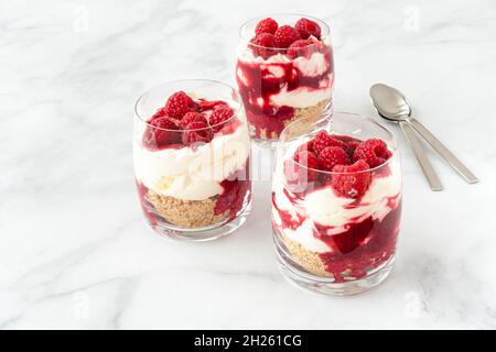 Dessert sans gâteau au fromage framboise dans trois verres sur fond de marbre blanc avec espace de copie.Version horizontale. Banque D'Images