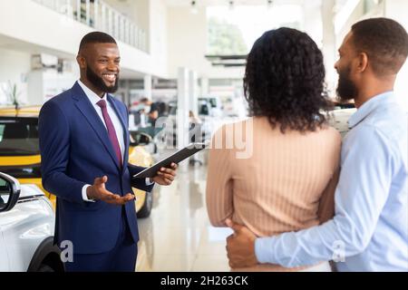 Couple de conseillers en vente de véhicules noirs souriants au Centre des concessionnaires automobiles Banque D'Images