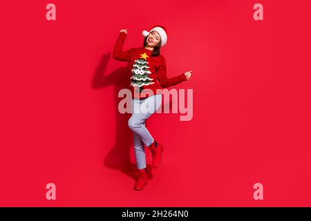 Photo de drôle douce jeune femme vêtue pull-over d'impression célébrant la danse de noël isolé rouge couleur fond Banque D'Images