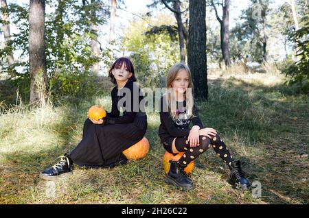 Deux sœurs heureuses à la forêt d'Halloween.Drôle d'enfants en costumes de carnaval en plein air à Halloween trick ou traiter.Joyeux Halloween ! Banque D'Images