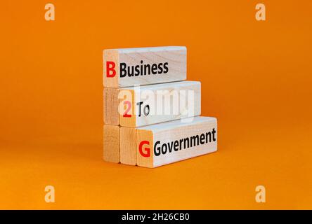 Symbole B2G entre les entreprises et le gouvernement.Concept mots 'B2G - affaires au gouvernement' sur des blocs de bois sur un beau fond orange.Business et B2G bu Banque D'Images