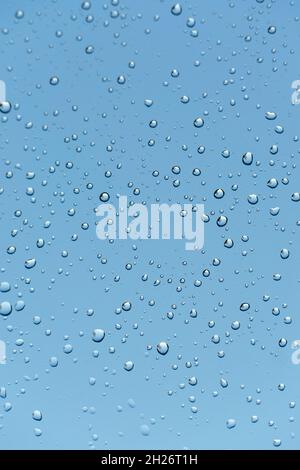 Gouttes de pluie sur la fenêtre, ciel bleu moody, plan vertical Banque D'Images