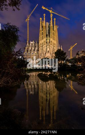 Sagrada Familia - Une vue nocturne verticale de la façade est de la Nativité de la Basílica de la Sagrada Família se reflète dans un petit étang, Barcelone, Espagne. Banque D'Images