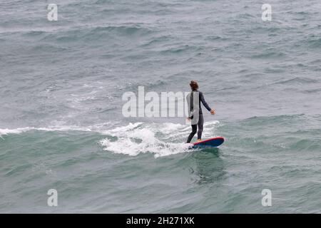 la surfeuse en combinaison attrape une vague Banque D'Images