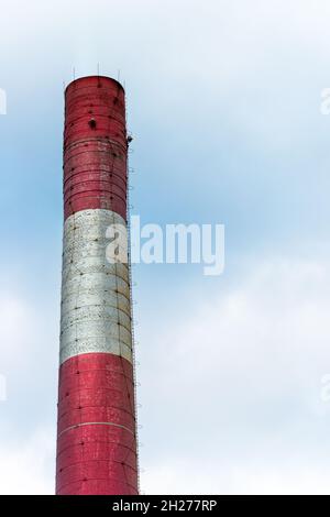 Ancienne cheminée d'usine de briques peinte en blanc et rouge contre bleu, ciel nuageux Banque D'Images