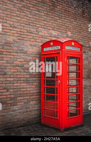 Kiosque téléphonique public britannique traditionnel rouge ou stand avec mur de briques en arrière-plan, Bushmills ville, Irlande du Nord Banque D'Images