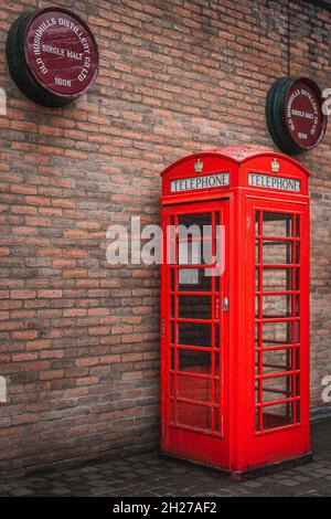 Bushmills, Irlande du Nord, août 2019 cabine téléphonique publique britannique traditionnelle avec des barils de whisky de Bushmills au-dessus dans le centre des visiteurs de la distillerie Banque D'Images