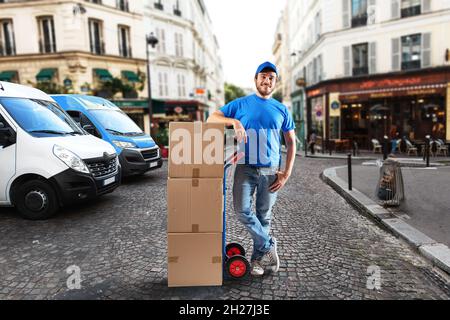 Homme avec uniforme bleu devant les magasins pour la livraison et le ramassage des marchandises Banque D'Images