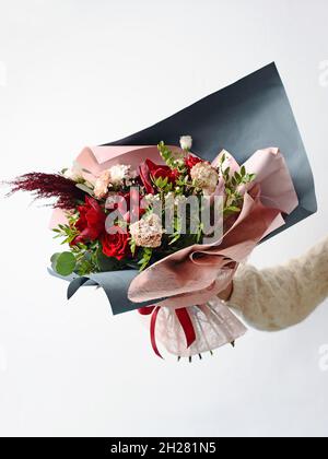 Beau cadeau de bouquet rouge fleuri.Diverses fleurs fraîches et plantes décoratives en papier rose et noir.Isolé sur fond blanc. Banque D'Images