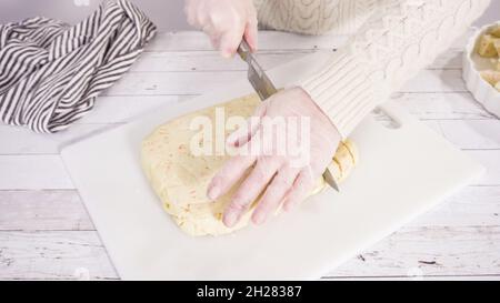 Étape par étape. Coupe de fudge de canne à sucre fait maison sur un tableau de découpe blanc. Banque D'Images