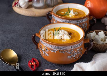 Soupe à la crème de potiron avec feta dans deux bols bruns sur fond sombre Banque D'Images