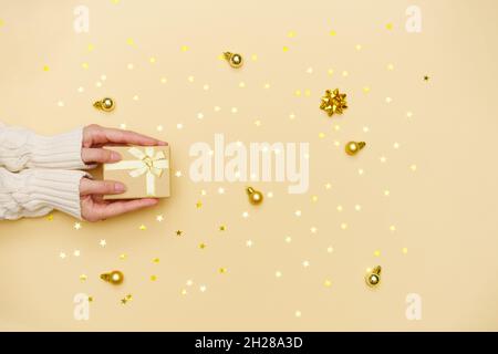 Les femmes tiennent la boîte cadeau joyeux noël sur fond jaune décoré de vacances, femme préparant la surprise, nouvel an hiver joyeux confetti dorés des étoiles, concept de vacances vrai, vue du dessus Banque D'Images