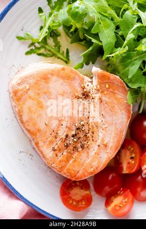 Steak de thon rose frit servi avec des légumes sur une assiette, vue du dessus.Repas sain Banque D'Images