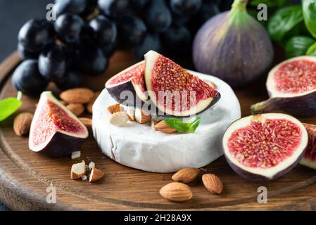 Camembert, figues, amandes et raisins, sur un plateau de service en bois, vue rapprochée.Hors-d'œuvre gastronomique, en-cas au vin Banque D'Images
