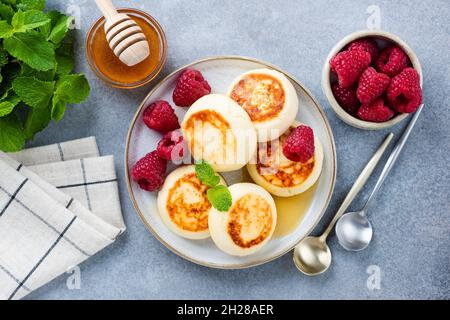 Beignets de fromage cottage ou sirop servi avec du miel et des framboises, vue sur le dessus.Cuisine ukrainienne et russe Banque D'Images