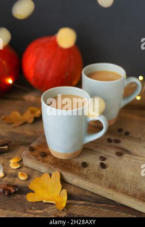 Deux cafés de citrouille aromatisés aux épices en céramique sur une table en bois avec des citrouilles d'orange en arrière-plan.Bokeh.Ambiance d'automne.Temps de boire ho Banque D'Images