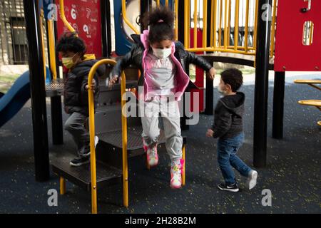 Éducation préscolaire 4-5 ans terrain de jeu fille saut hors de l'équipement de terrain de jeu, portant un masque facial pour protéger contre l'infection Covid-19 Banque D'Images